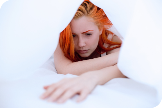 Une femme sous la couette qui a un visage triste